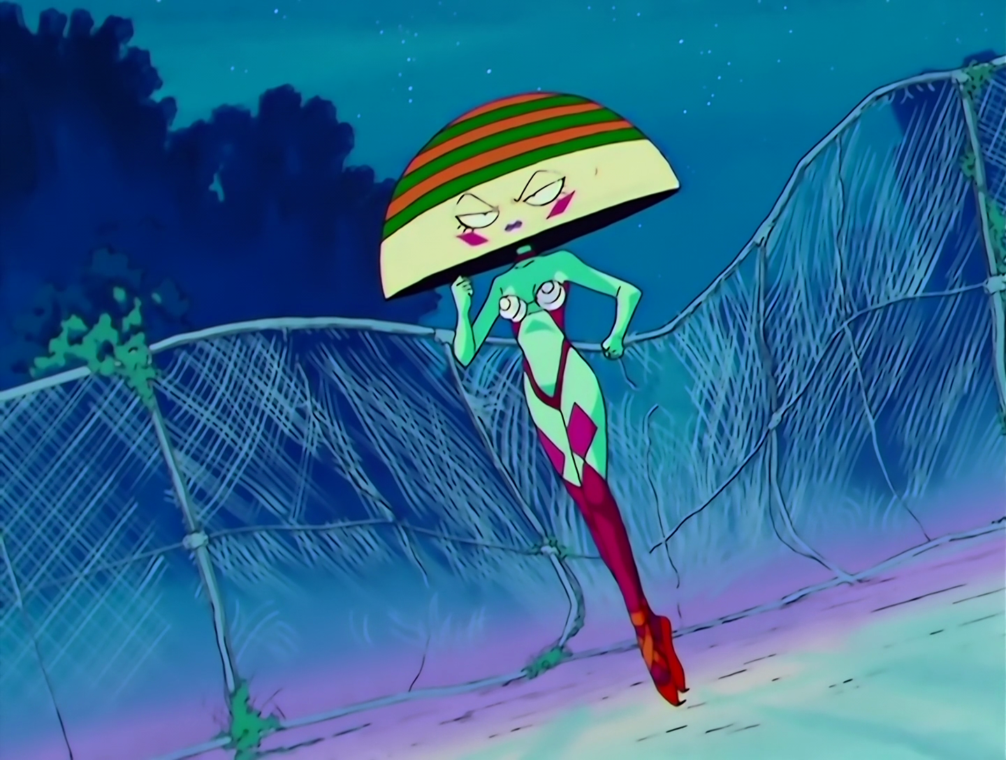 Elephanko now has a human form… sort of. Her skin is turquoise, and she has purple stockings, plus a purple bikini with most of the front cut out, with the top section consisting of two white cups decorated with concentric circles. Her head is enormous and dome shaped, basically the upper section of the ball. Her face is pale yellow and the section above her face has green and orange stripes. She’s quite a sight.